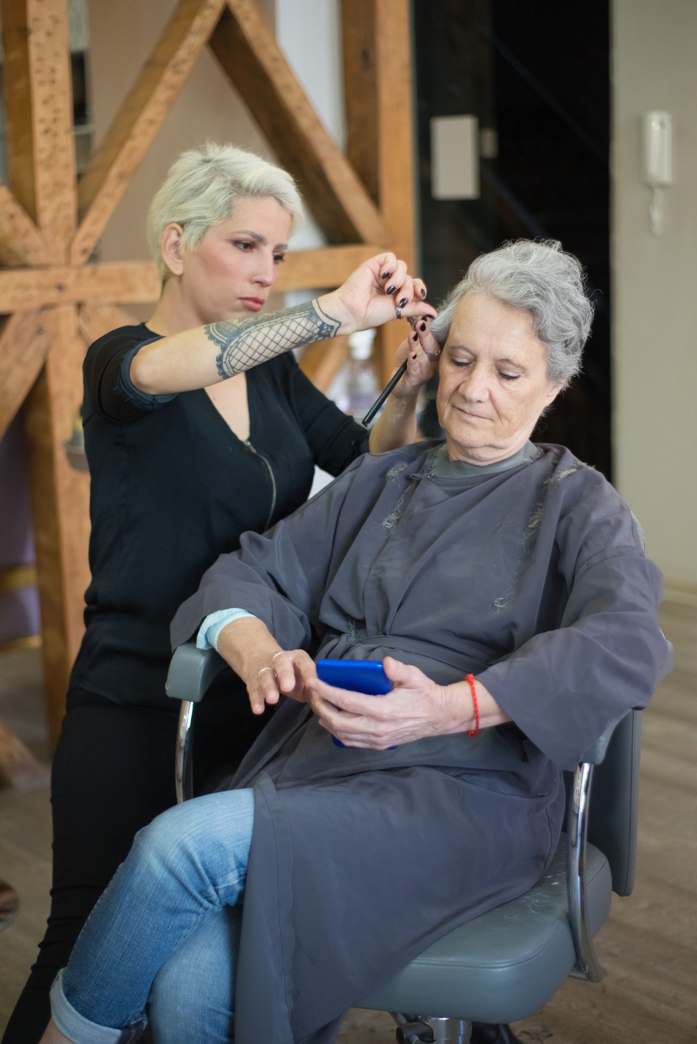 Hairdresser working with an older customer using a phone in a salon